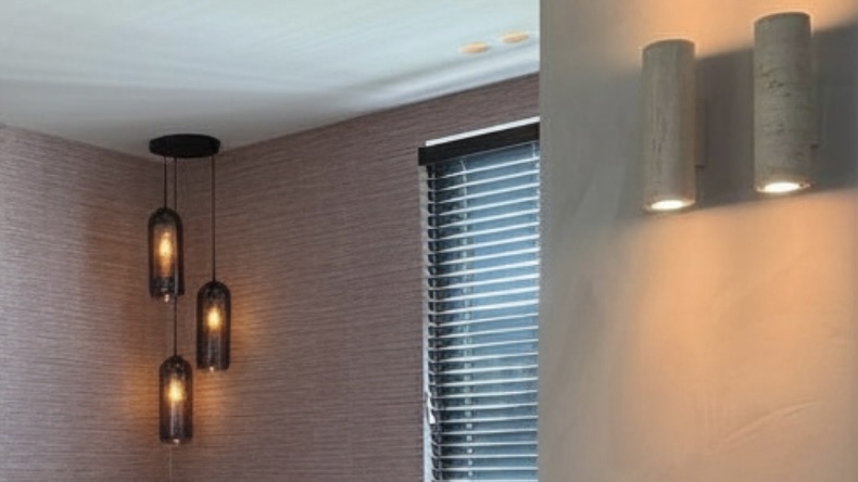 Detail van verlichting bij het raam: twee spots, twee wandlampen en een hanglamp in de hoek.